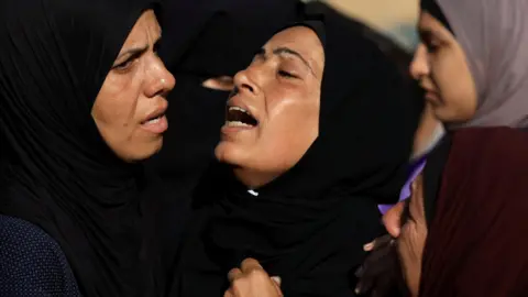 Reuters Palestinian women mourn at the funeral of people who were killed while seeking aid in northern Gaza, at al-Shifa hospital, Gaza City (18 June 2025)