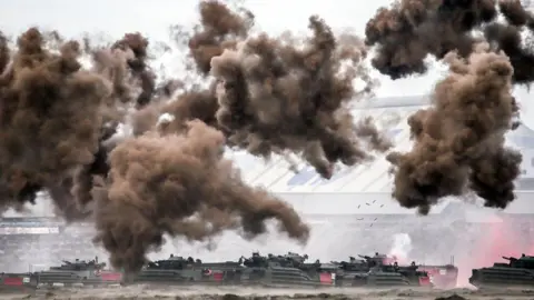 Getty Images Clouds of brown smoke float in the air as assault amphibious vehicles trundle across a beach and fire at targets during the 2023 Han Kuan Taiwan military exercise.
