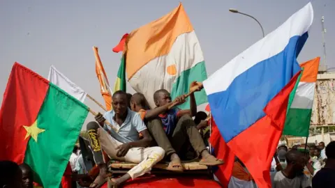 EPA Protesters display Russia's and Niger's flags as they sit on top of a vehicle amid a demonstration.