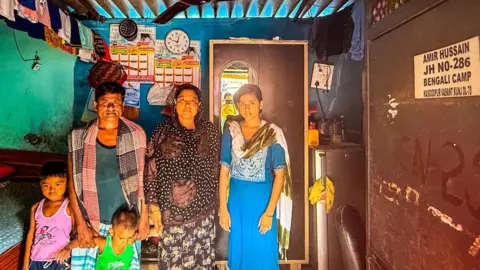 Zoya Mateen/BBC A Bengali-Muslim family - comprising a husband and wife along with their three children - pose inside their home in a slum in Delhi 