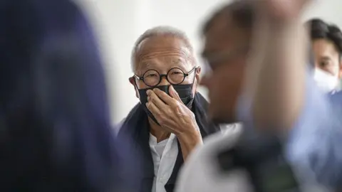 Getty Images Ong Beng Seng wearing a black mask and round spectacles. He is covering his mouth with his hand.
