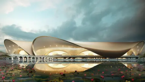 Adani Airport Holdings Limited Image of the lotus shaped exterior of the Navi Mumbai International Airport, lit up at dusk. 