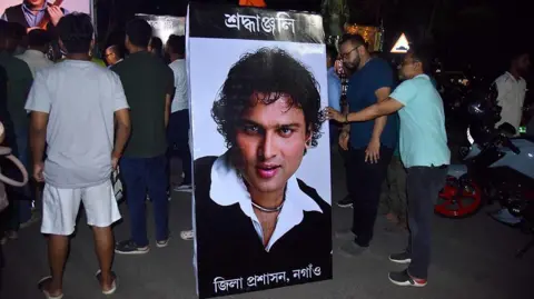Getty Images A poster of Indian singer-composer Zubeen Garg, surrounded by fans in Assam's Nagaon town, paying tributes after the news of his death broke out on 19 September