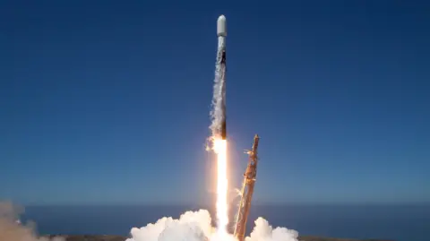 Space X A satellite being launched into the space by a Space X rocket on a blue clear day.