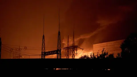 Getty Images A long shot of a power lines in front of a bright orange blaze