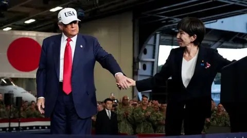 Getty Images U.S. President Donald Trump leads Japanese Prime Minister Sanae Takaichi off the stage after speaking to troops aboard USS George Washington at Fleet Activities Yokosuka on October 28, 2025 in Yokosuka, Japan. Trump is visiting Japan, fresh off an appearance at the ASEAN summit in Malaysia, and will next travel to South Korea for the APEC meetings.