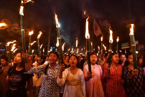 AFP via Getty Images  Members of the All Assam Students' Union (AASU) take part in a torch rally as they protest against the implementation of the Citizenship Amendment Act (CAA) in Guwahati on March 12, 2024. India's interior ministry said March 11 it was enacting a citizenship law that critics say discriminates against Muslims, just weeks before the world's most populous country heads into a general election. (Photo by Biju BORO / AFP) (Photo by BIJU BORO/AFP via Getty Images)
