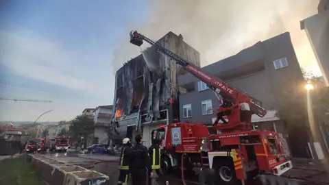 Kocaeli Metropolitan Municipality Firefighters on a cherry picker extinguish flames at the perfume warehouse