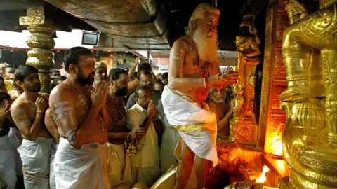 Vivek Nair Sabarimala temple priests carry out rituals in this photo which also shows some gold-clad statutes
