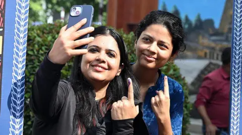 Getty Images Two women click a selfie outside a polling booth in Bihar's capital Patna with inks on their fingers that show they have cast their votes. 