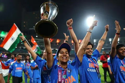 Alex Davidson-ICC/ICC via Getty Images  Jemimah Rodrigues of India celebrates with the ICC Women's Cricket World Cup trophy after her team's victory in the ICC Women's Cricket World Cup India 2025 Final match between India and South Africa at Dr. DY Patil Sports Academy on November 02, 2025 in Navi Mumbai, India. (Photo by Alex Davidson-ICC/ICC via Getty Images)