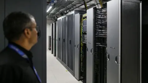 Bloomberg via Getty Images Server room at the Yotta data centre in Navi Mumbai, India, with a spectacled employee pictured on the left.  