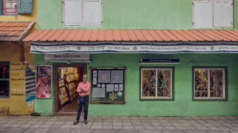 Dinesh Madhavan Thaha Ibrahim stands outside his shop in Fort Kochi