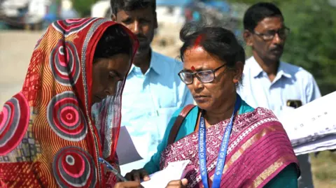 Getty Images Booth Level Officers (BLOs) distribute enumeration forms as a part of the Election Commission of India's Special Intensive Revision (SIR), at a fisherman's village on the Mousuni Island in West Bengal on November 10, 2025.