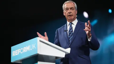 EPA Nigel Farage gives a speech from behind a turquoise Reform UK podium at the party's annual conference in Birmingham in September.