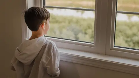 Getty Images Stock image of child looking out of a window