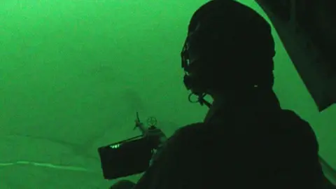 BBC A night-vision view of a soldier sitting in a helicopter 