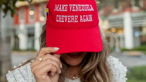 Getty Images A resident shows a Maga-style red baseball cap with the words "MAKE VENEZUELA CHEVERE [great] AGAIN" during celebrations in a Venezuelan enclave in Miami, following the raid and removal of Maduro and his wife