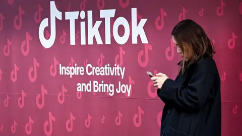 Getty Images A woman uses her phone in front of Tiktok's booth during the World Economic Forum (WEF) annual meeting in Davos 